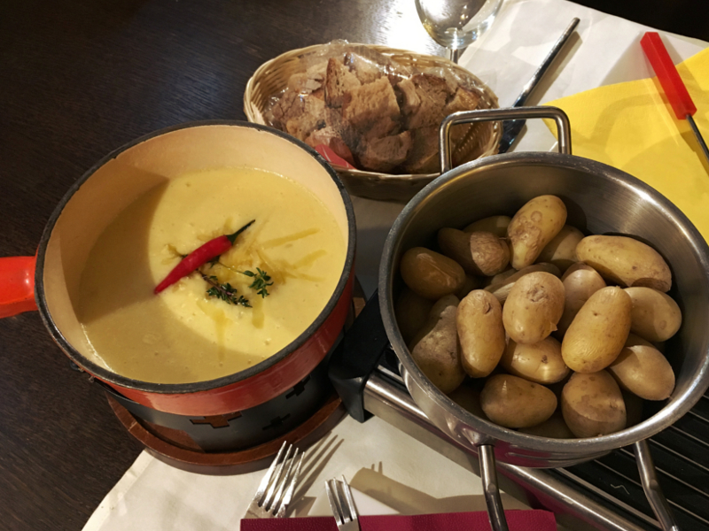 Organic Swiss alpine cheese fondue bubbling in caquelon